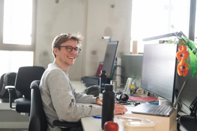 young man behind computer in office